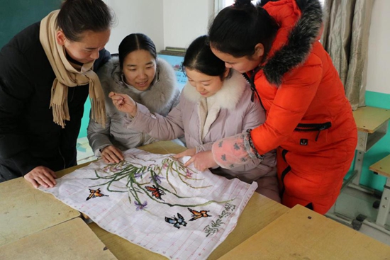 1513669805874751.jpg 輔導(dǎo)老師正在一針一線傳授十字繡手法.jpg